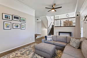 Carpeted living room with ornamental molding, ceiling fan, and a fireplace