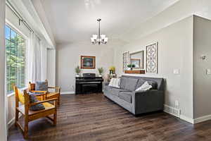 Living room featuring a notable chandelier, a textured ceiling, dark hardwood / wood-style floors, and lofted ceiling