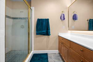 Bathroom with a shower with shower door, vanity, and tile floors