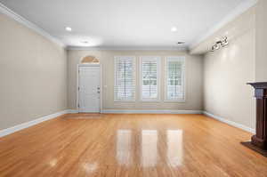 Unfurnished living room featuring light hardwood / wood-style floors and crown molding