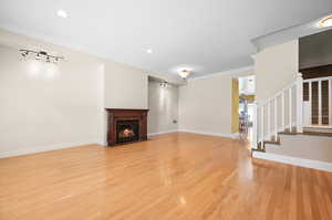 Unfurnished living room featuring crown molding, rail lighting, and light hardwood / wood-style flooring