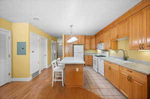 Kitchen with a center island, white appliances, pendant lighting, sink, and a kitchen bar