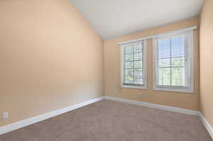 Spare room with a healthy amount of sunlight, vaulted ceiling, and carpet floors