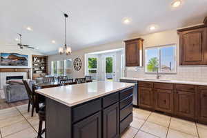 Kitchen with a fireplace, backsplash, hanging light fixtures, a center island, and sink