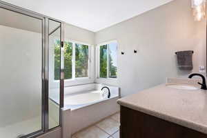 Bathroom featuring tile floors, separate shower and tub, and vanity