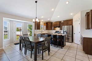 Tiled dining area featuring a notable chandelier, sink, lofted ceiling, and plenty of natural light