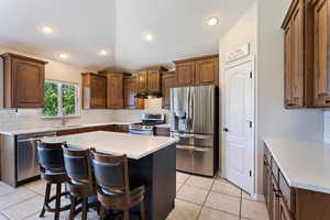 Kitchen with backsplash, appliances with stainless steel finishes, sink, and light tile floors