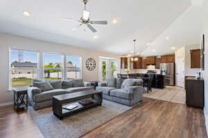 Living room featuring high vaulted ceiling, light hardwood / wood-style flooring, and ceiling fan with notable chandelier