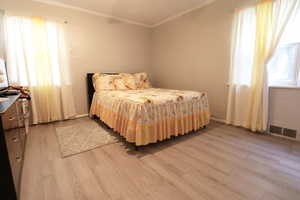 Bedroom with hardwood / wood-style floors and crown molding