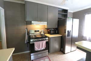 Kitchen featuring crown molding, stainless steel appliances, gray cabinets, ceiling fan, and light tile floors