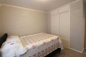 Bedroom with crown molding, hardwood / wood-style flooring, and a closet