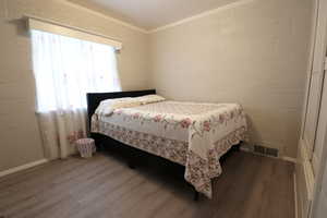 Bedroom with hardwood / wood-style flooring and crown molding