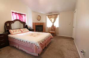 Bedroom featuring carpet floors, lofted ceiling, a fireplace, and multiple windows