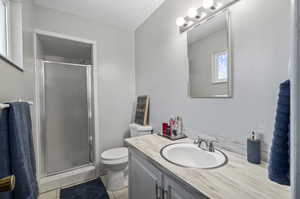 Bathroom with an enclosed shower, oversized vanity, toilet, and tile floors