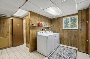 Washroom featuring separate washer and dryer, wooden walls, washer hookup, and light tile floors