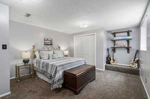 Bedroom with a closet, a textured ceiling, and carpet floors