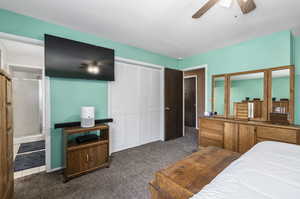 Bedroom with ceiling fan, a closet, and dark carpet