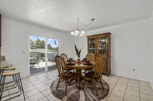 Tiled dining space featuring a textured ceiling and a chandelier