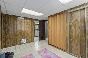 Interior space with light tile flooring, wooden walls, and a paneled ceiling