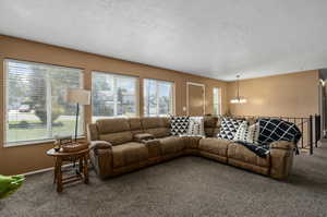 Carpeted living room with a chandelier and a textured ceiling