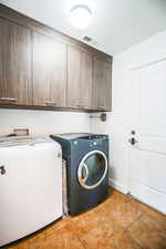 Laundry area featuring cabinets, separate washer and dryer, and light tile patterned floors