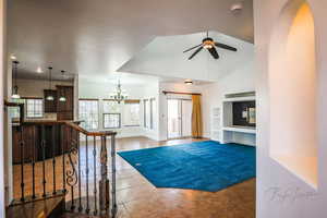 Tiled foyer featuring ceiling fan with notable chandelier, high vaulted ceiling, and a healthy amount of sunlight