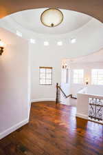 Empty room with dark hardwood / wood-style flooring and a high ceiling