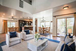 Tiled living room featuring ceiling fan with notable chandelier and a towering ceiling