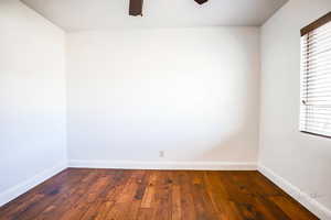 Unfurnished room featuring a wealth of natural light, dark hardwood / wood-style floors, and ceiling fan