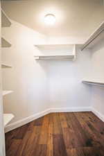 Spacious closet with dark wood-type flooring and a wall mounted AC