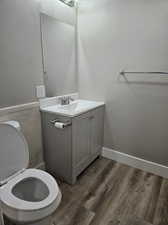 Bathroom featuring wood-type flooring, oversized vanity, and toilet