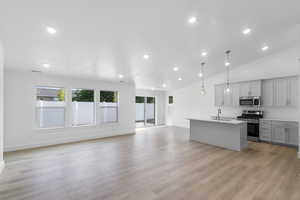 Kitchen with a center island with sink, backsplash, light wood-type flooring, and appliances with stainless steel finishes