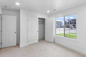 Unfurnished bedroom with light colored carpet and a closet