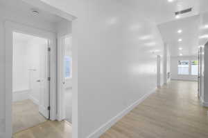 Hallway featuring light wood-type flooring and a healthy amount of sunlight