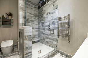 Bathroom featuring an enclosed shower, toilet, and radiator