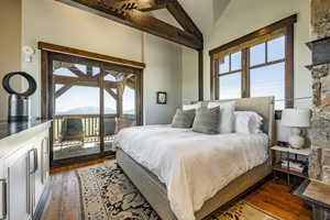 Bedroom with access to outside, multiple windows, a mountain view, and dark wood-type flooring