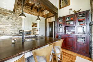 Kitchen featuring a high ceiling, light wood-type flooring, decorative light fixtures, beam ceiling, and stainless steel appliances