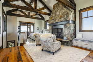 Living room with high vaulted ceiling, light wood-type flooring, a fireplace, and a wealth of natural light