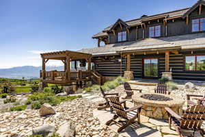 Rear view of property with a deck with mountain view, a pergola, an outdoor fire pit, and a patio area