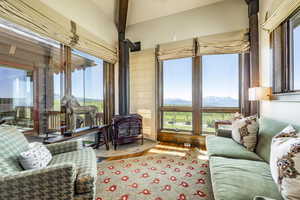 Living room featuring a mountain view, wood-type flooring, a wood stove, and beamed ceiling