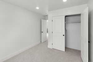 Unfurnished bedroom featuring a closet and light carpet