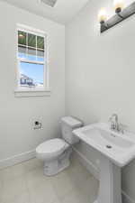 Bathroom with toilet, sink, and tile patterned flooring