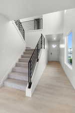 Stairs with wood-type flooring and a high ceiling