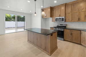 Kitchen with appliances with stainless steel finishes, a kitchen island, decorative backsplash, and light hardwood / wood-style floors