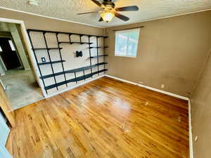 Interior space with a textured ceiling, ceiling fan, and hardwood / wood-style floors