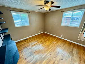 Unfurnished bedroom featuring a textured ceiling, ceiling fan, and hardwood / wood-style floors