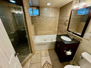 Full bathroom featuring tile floors, plus walk in shower, toilet, and vanity with extensive cabinet space