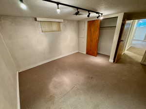 Interior space featuring a closet, carpet floors, a textured ceiling, and track lighting