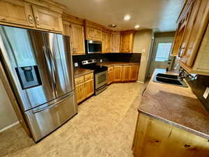 Kitchen with appliances with stainless steel finishes, sink, tasteful backsplash, and light tile floors