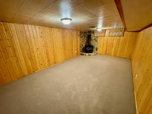 Basement featuring carpet, wood walls, and a wood stove